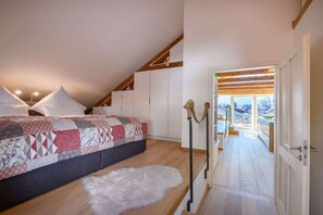 A bedroom with a bed, a white furry rug, and a view of a balcony. - Holiday apartment with 2 bedrooms (Garmisch-Partenkirchen)