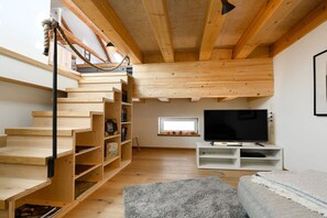 Une pièce avec un escalier en bois, un téléviseur à écran plat et une fenêtre.
