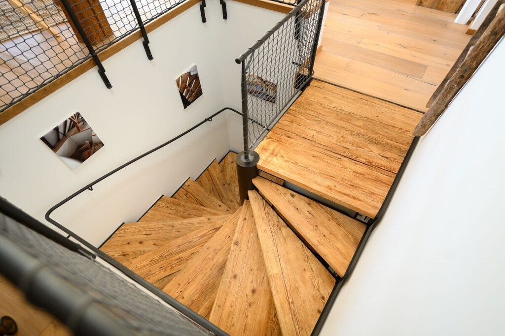Un escalier en colimaçon avec des marches en bois et des rampes en métal.