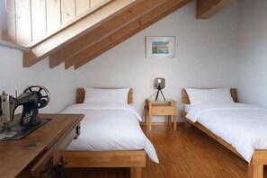 A bedroom with two beds, a sewing machine, a lamp, and a framed picture on the wall. - Water Castle Lake Constance (Wasserburg)