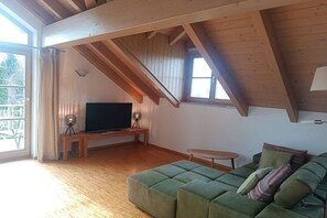 A cozy living room with a television, a green sofa, and a wooden ceiling. - Water Castle Lake Constance (Wasserburg)