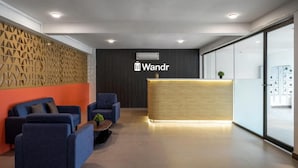 En moderne receptionsafdeling med en træreception, blåt siddearrangement og et geometrisk vægdesign.