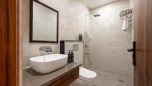 Et stilfuldt badeværelse med en stor hvid vask, toilet og bruseniche.