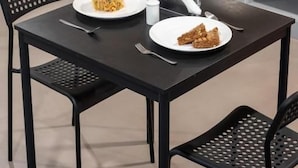 En spiseplads med et bord dækket til to, en buffet med forskelligt mad og en vanddispenser.