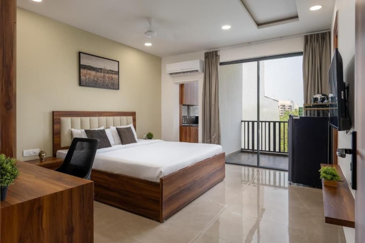 Quarto de hotel com cama, escrivaninha, televisão e varanda com vista.