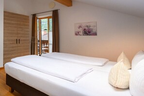 A bedroom with a bed, a wardrobe, and a window with curtains. - Holiday apartment with 2 bedrooms (Farchant)
