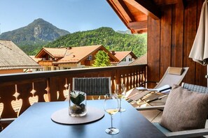 Een balkon met een tafel, twee stoelen en een glas witte wijn.