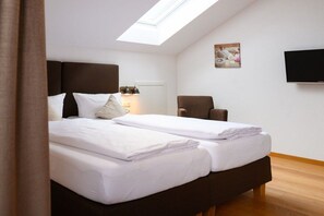 A bedroom with two beds, a skylight, a chair, a flat-screen TV, and a painting on the wall. - Holiday apartment with 2 bedrooms (Farchant)