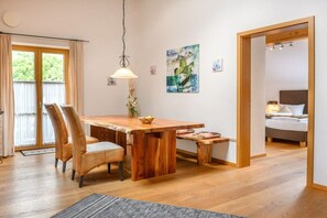 A wooden dining table with chairs, a hanging light fixture, and artwork on the wall. - Holiday apartment with 2 bedrooms (Farchant)