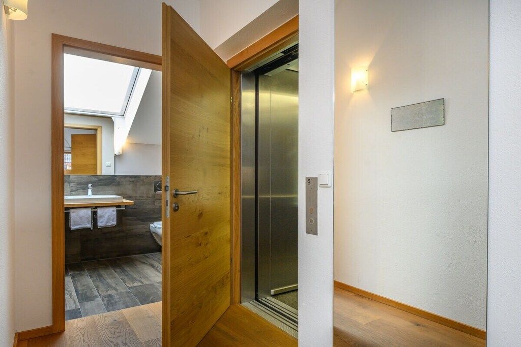 Ein modernes Badezimmer mit Holztür, sichtbarer Toilette und Dachfenster.