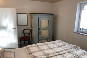 A bedroom with a bed, a wardrobe, a chair, and a window. - Holiday apartment with 1 bedroom (Segnitz)