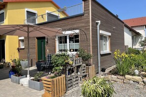 A residential building with a balcony, outdoor seating, and potted plants. - Holiday apartment with 1 bedroom (Segnitz)