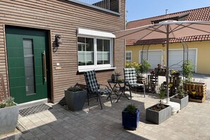 A patio area with outdoor seating, a green door, and a window with blinds. - Holiday apartment with 1 bedroom (Segnitz)