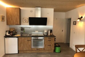 A compact kitchen with a built-in oven, a small refrigerator, and a coffee maker. - Holiday apartment with 1 bedroom (Segnitz)