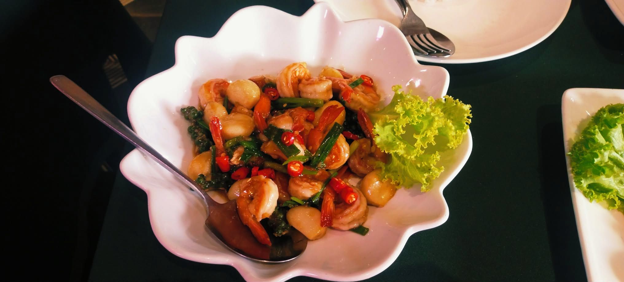 Un plato de comida con cuchara, tenedor y una ensalada en una mesa.
