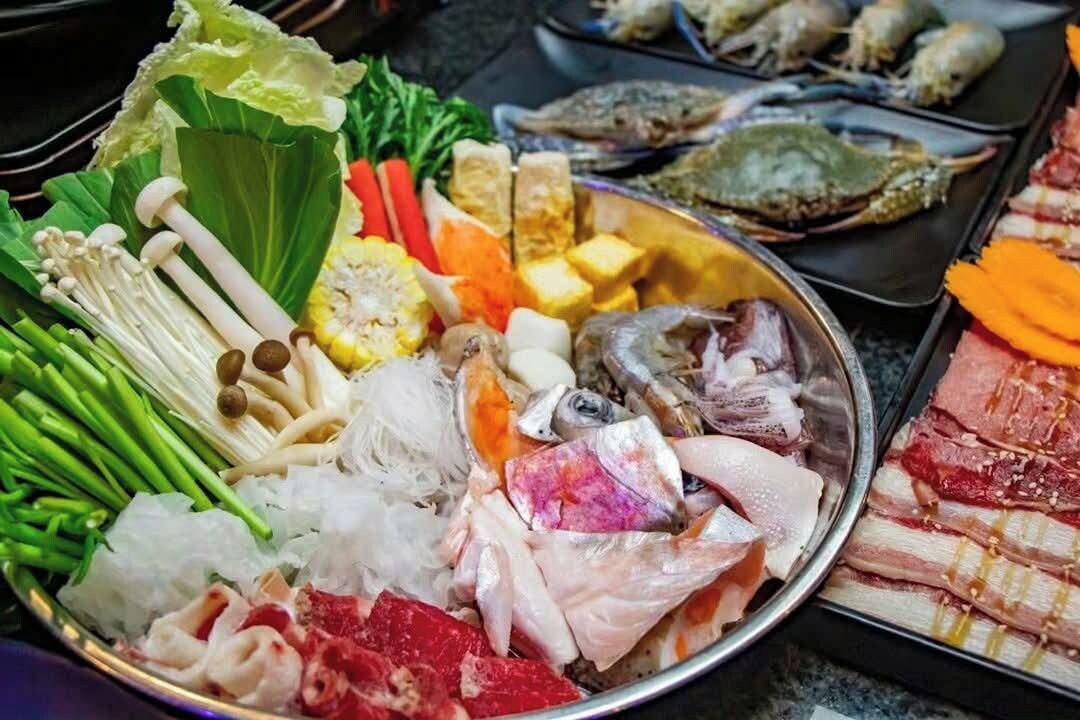 Diversos frutos do mar crus e vegetais em uma bandeja de metal.