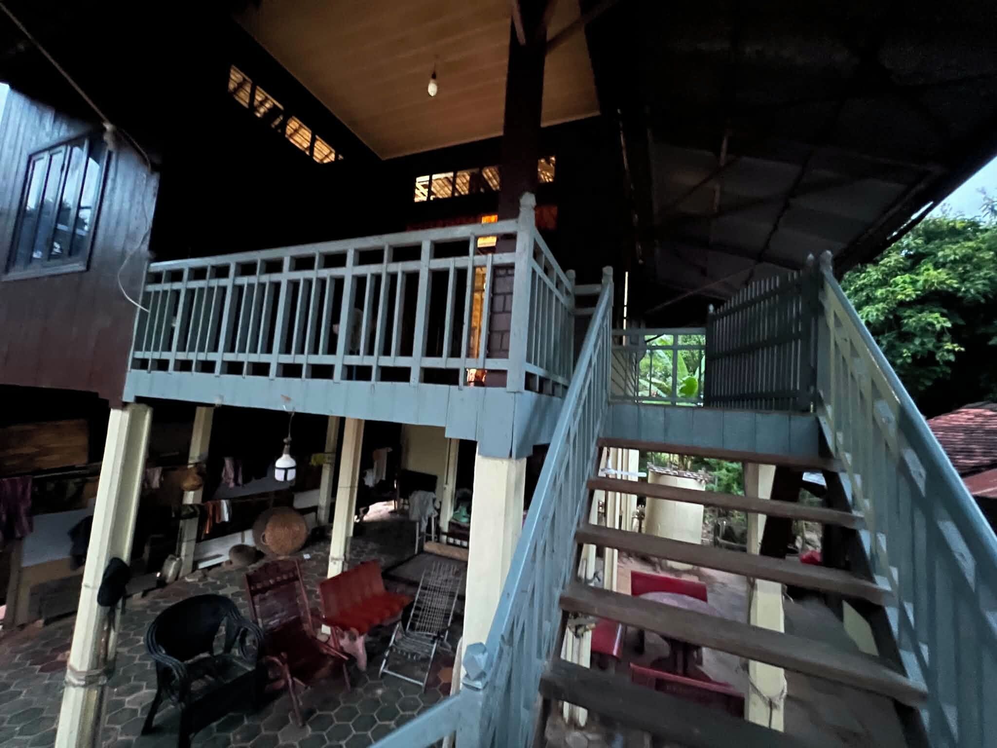 A covered outdoor area with a wooden staircase leading to a balcony.