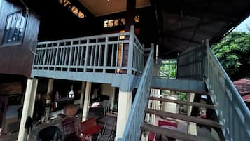 A covered outdoor area with a wooden staircase leading to a balcony.