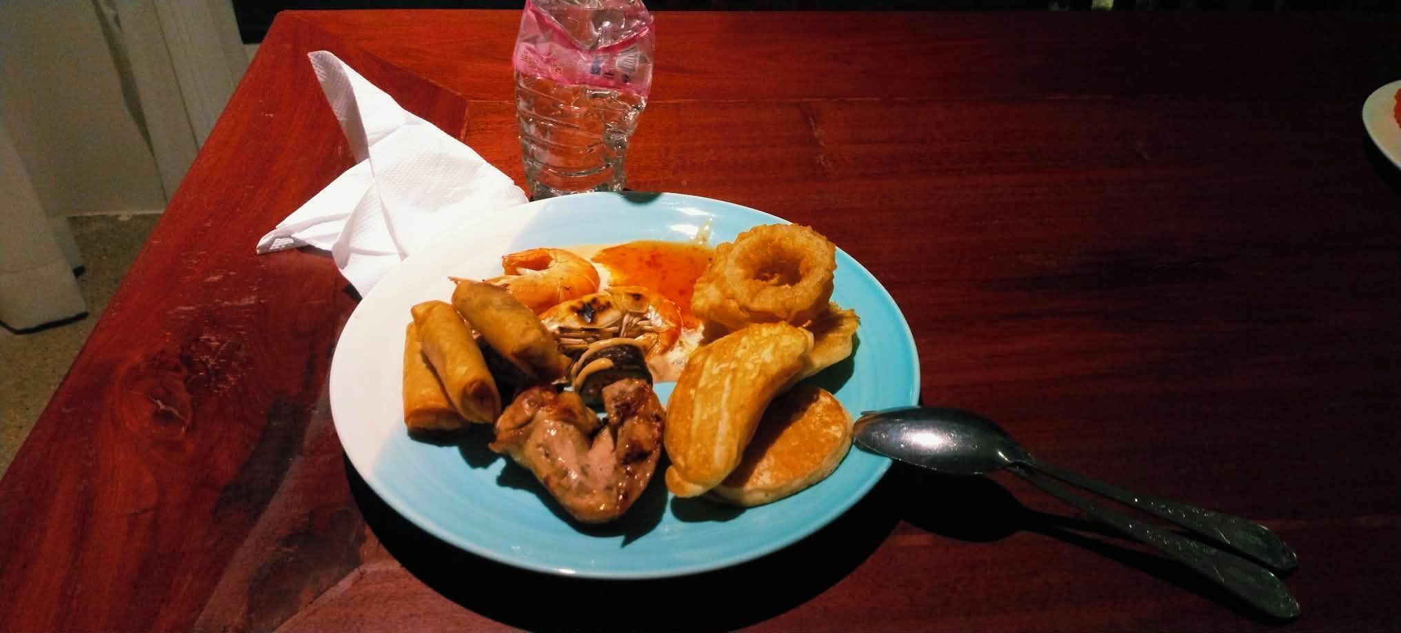 A plate of food with a spoon on a wooden table.