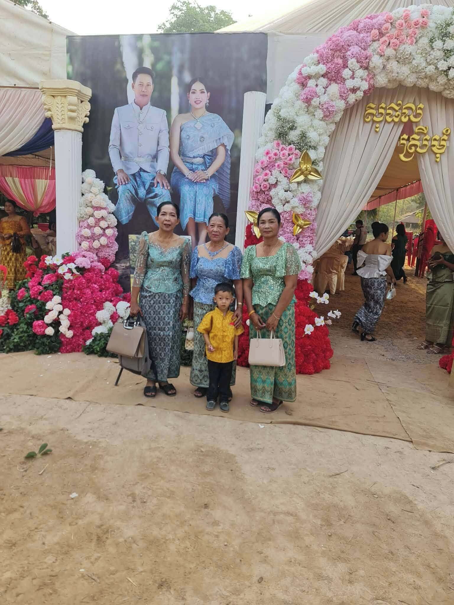 Un grupo de personas frente a un fondo decorado con arreglos florales y un cartel.