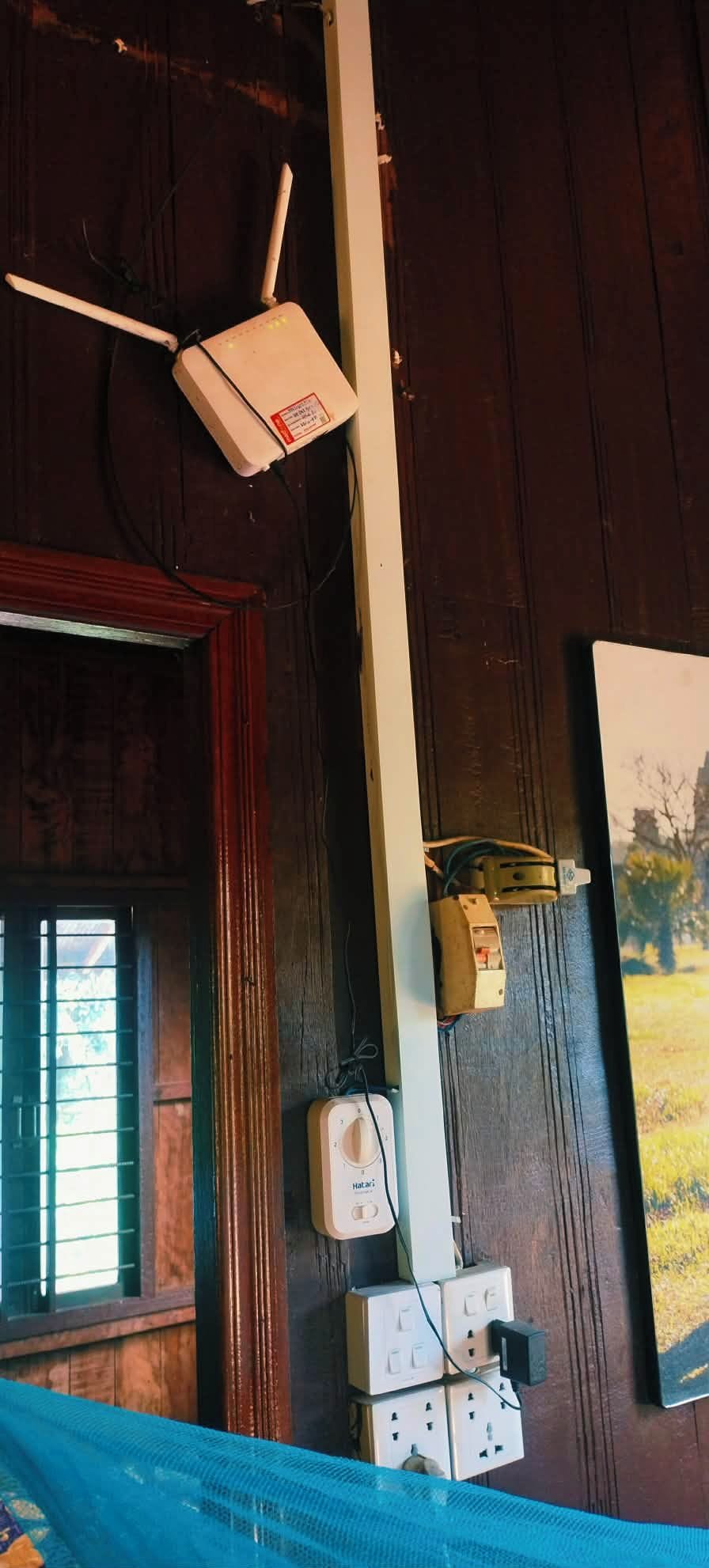 A room with a wooden wall, a window with blinds, a ceiling fan, and electrical outlets.