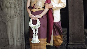 A couple standing in front of an ancient temple entrance with detailed carvings.