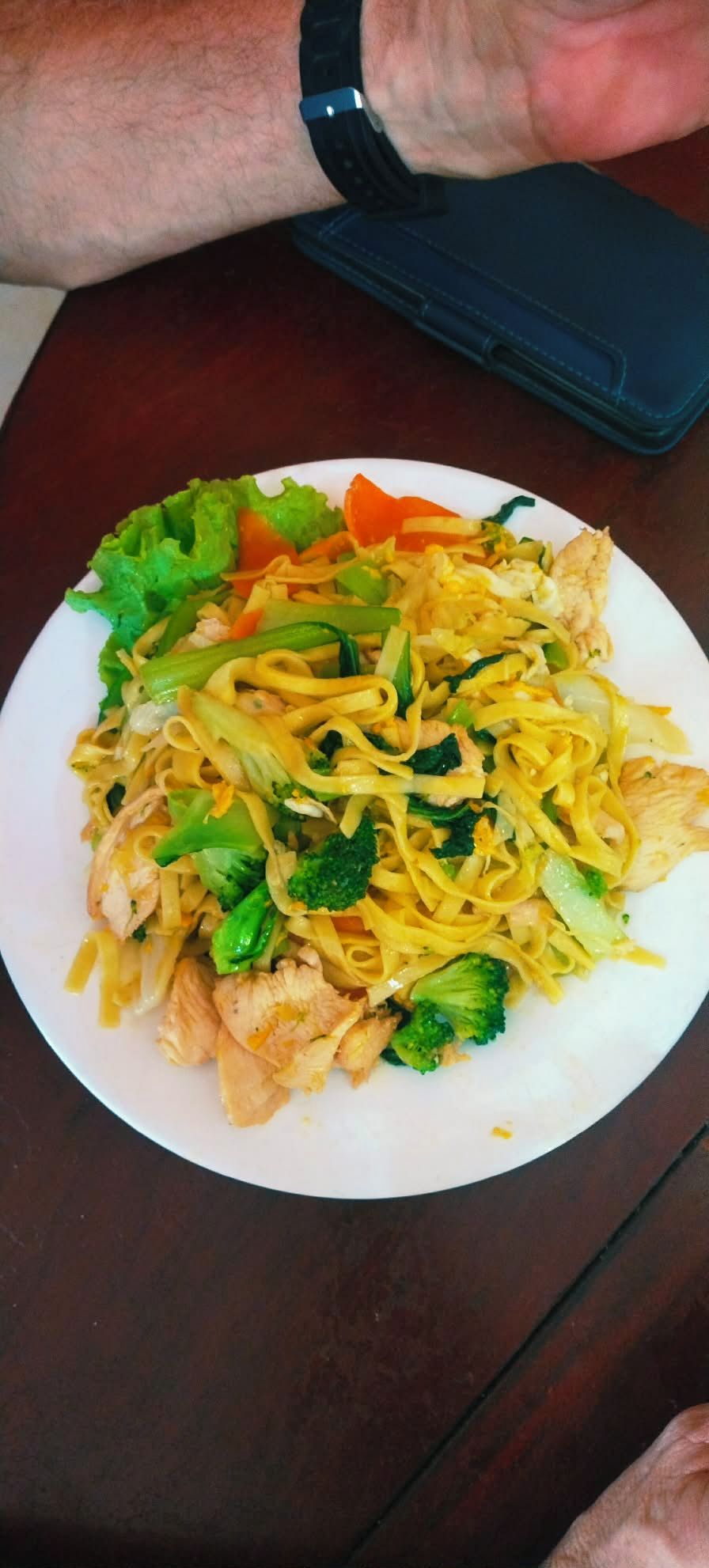 Une assiette de nouilles sautées aux légumes et au poulet, servies dans une assiette blanche.