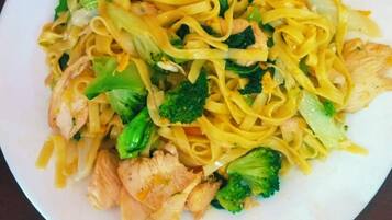A plate of stir-fried noodles with vegetables and chicken on a white plate.