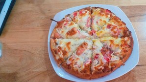 A pizza on a white plate on a wooden table.