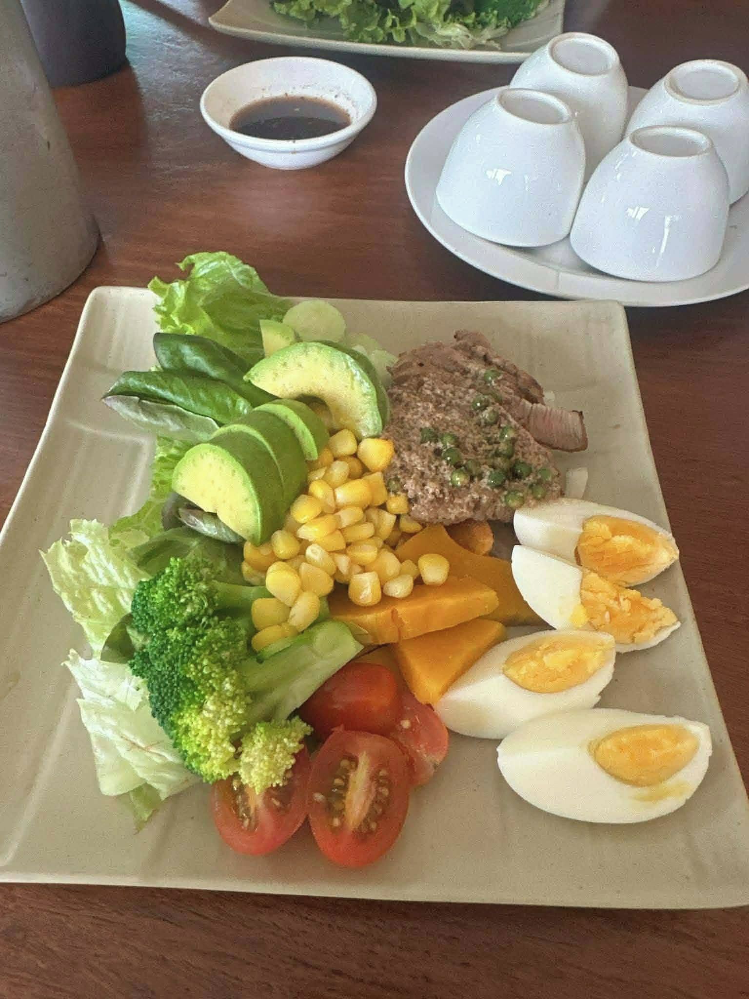 Prato com diversos alimentos, incluindo carne, ovos, milho, tomates e legumes.