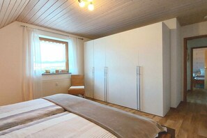 A bedroom with a bed, a window, a wardrobe, and a chair. - Holiday apartment with 2 bedrooms (Harsdorf)