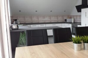 A modern kitchen with a wooden countertop, black chairs, and a microwave. - Holiday apartment with 3 bedrooms (Werbachhausen)