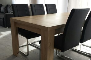 Ein Esstisch mit vier Stühlen, ein Sofa und ein Fenster mit Vorhängen.