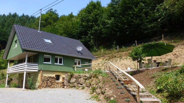 A house with a sloped roof, a satellite dish, a porch, and a staircase leading to a green umbrella. - Holiday home in Oberharmersbach with sauna (Oberharmersbach)
