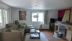 A living room with a sofa, a coffee table, a fireplace, and a painting on the wall. - Holiday home in Oberharmersbach with sauna (Oberharmersbach)