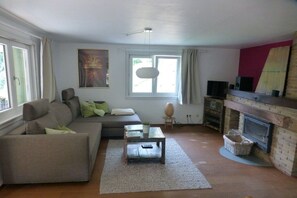Een woonkamer met een bank, een salontafel, een open haard en een schilderij aan de muur.