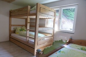 Llits superposats amb vistes per la finestra, un sòl de fusta i una petita taula de nit.