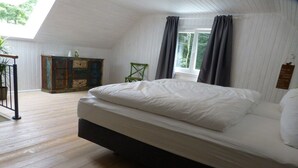A bedroom with a bed, a dresser, a chair, and a window with curtains. - Holiday home in Oberharmersbach with sauna (Oberharmersbach)