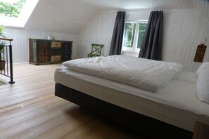 Een slaapkamer met een bed, een kaptafel, een stoel en een raam met gordijnen.