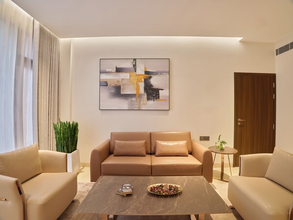 A modern living room with a sofa, a coffee table, and a painting on the wall. - Crowne Regency (Meenachil)