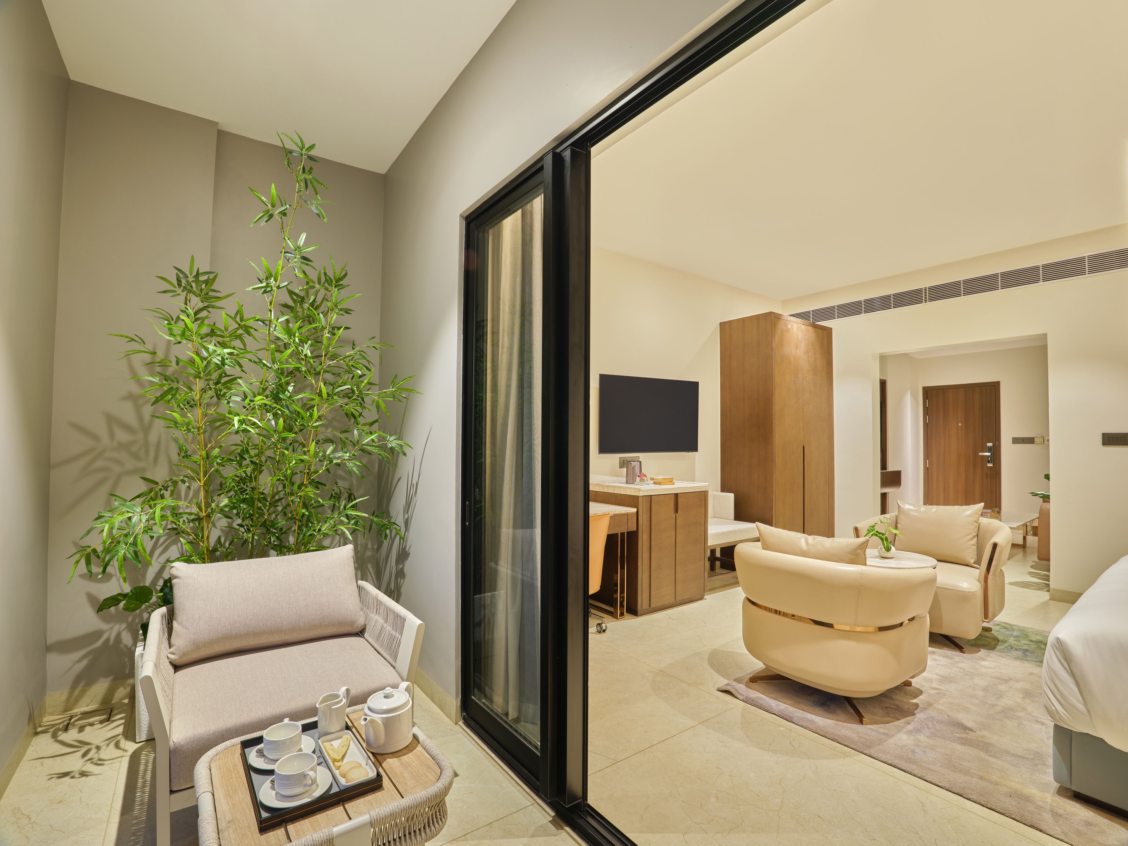 Una habitación de hotel moderna con sofá, sillón y zona de comedor con una bandeja de desayuno.