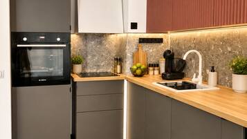 Una cocina moderna con horno Bosch, encimera de madera y lavaplatos integrado.