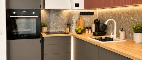 Una cocina moderna con horno Bosch, encimera de madera y lavaplatos integrado.