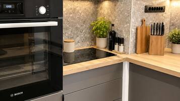A modern kitchen with a Bosch oven, a marble backsplash, and a wooden countertop.