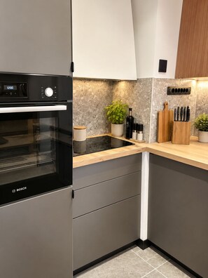 Una cocina moderna con horno Bosch, salpicadero de mármol y encimera de madera.