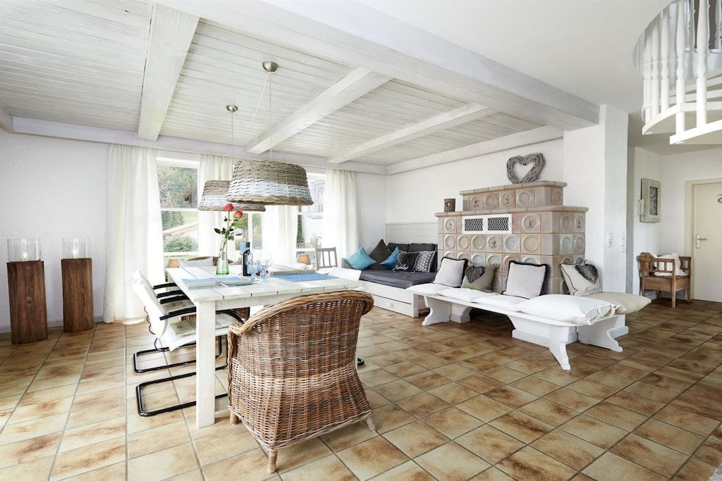 A spacious living area with a dining table, a sofa, and a wicker chair.