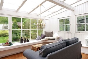 A conservatory with a built-in bench, a sofa, and a chandelier. - Holiday home "Nest" - Chalet Hentschel (Blaichach-Ettensberg)