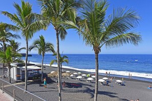 A beach with palm trees, umbrellas, and a clear view of the ocean. - Cozy house with garden and sea views (Tazacorte)