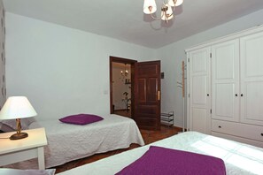 A bedroom with two beds, a nightstand, a lamp, a wardrobe, and a door leading to another room. - Cozy house with garden and sea views (Tazacorte)