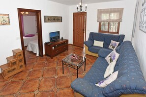 Een woonkamer met een bank, een televisie, een kleine tafel en een trap.